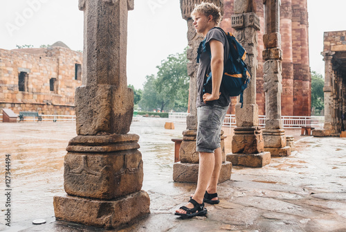 Young tourist man waits when intense rain stop on the yard of Qu