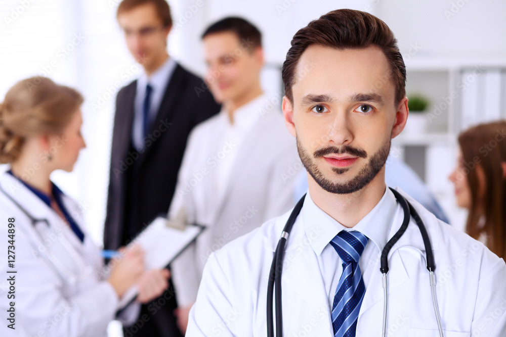 Friendly bearded male doctor with patients Friendly bearded male doctor with patients