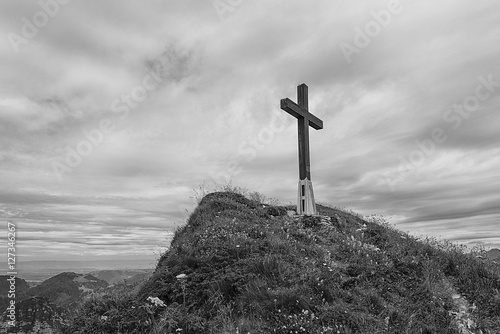 Canvas-taulu Black and white image of a cross on hillside in the Swiss alps