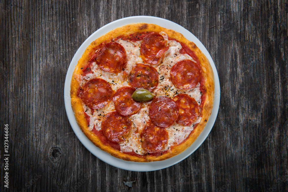 Pizza margarita with cheese and tomato isolated on rustic wooden table Pizza margarita with cheese and tomato isolated on rustic wooden table