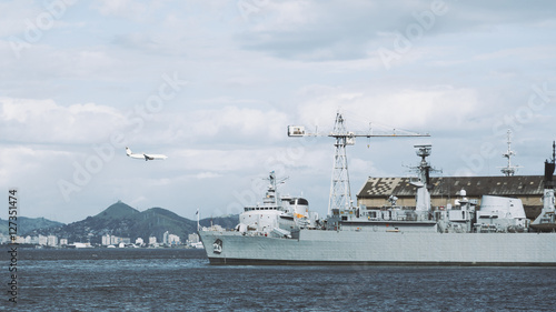 View of bay in Rio de Janeiro with military ship, crane and landing airplane, cloudy summer day, Brazil