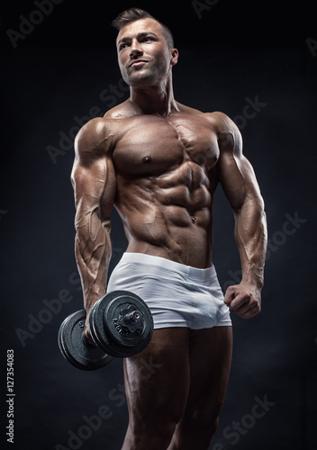 Muscular bodybuilder guy doing exercises with dumbbell