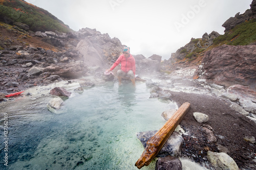 Woman soaking feet in hot spring after long hike in the mountains of Daisetsuzan National Park, Hokkaido, Japan