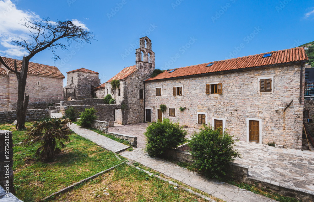 Holy Trinity Church yard in Budva Old Town. Traditional stone church and houses in Montenegro.
