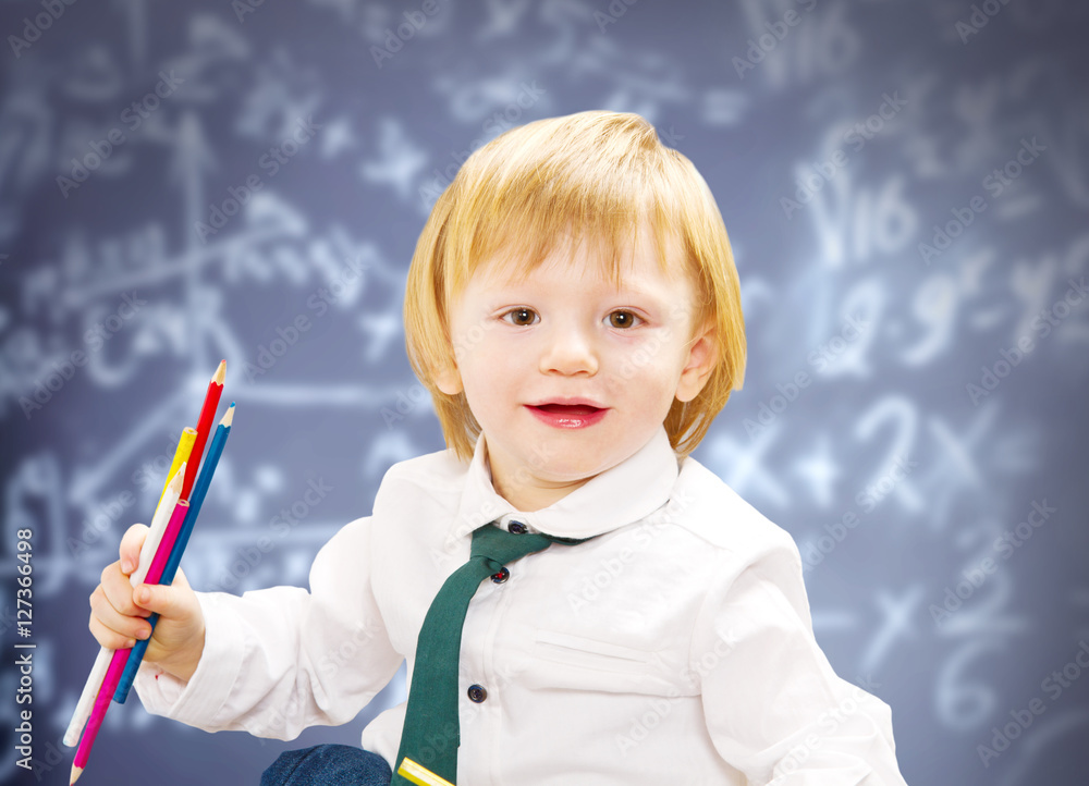 little boy with colored pencil with blackboard as background little boy with colored pencil with blackboard as background