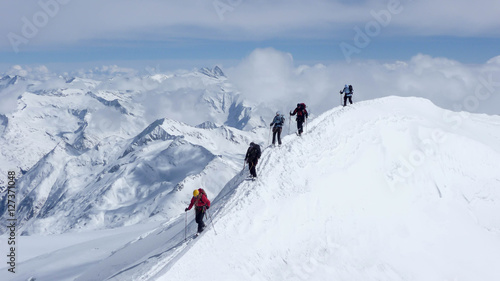 a mountain guide and clients on an exposed summit ridge during a winter ascent in the Austrian Alps © makasana photo