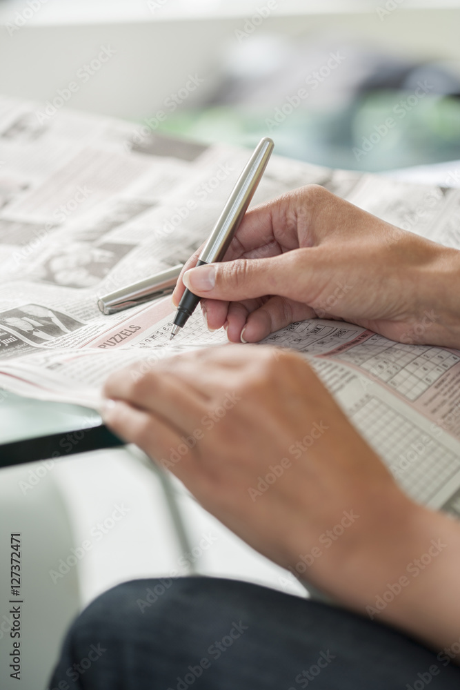 Woman making a crossword puzzle sitting on a table Woman making a crossword puzzle sitting on a table