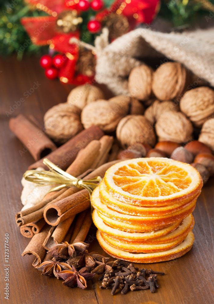 Fototapeta premium cinnamon sticks, nuts and dried orange slices, walnuts, pine tree on wooden background