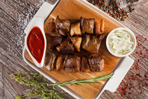 skewers of liver on a wooden board with white cup and around the