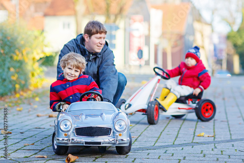 Two little kid boys and father playing with car, outdoors