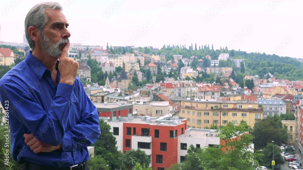 old senior man walks and thinks about something - city (buildings) in background old senior man walks and thinks about something - city (buildings) in background