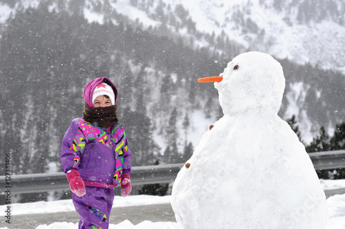 The girl near a big snowman. Cold day.