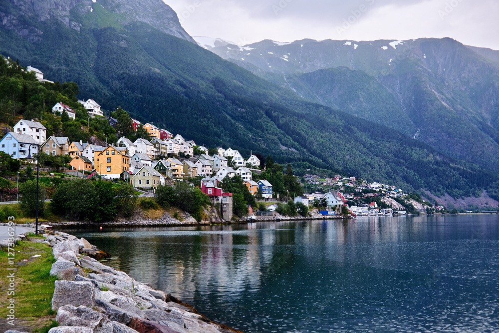 Fototapeta premium Colorful wood houses on a mountainside in Odda in Norway that leads to the inlet called Soerfjorden