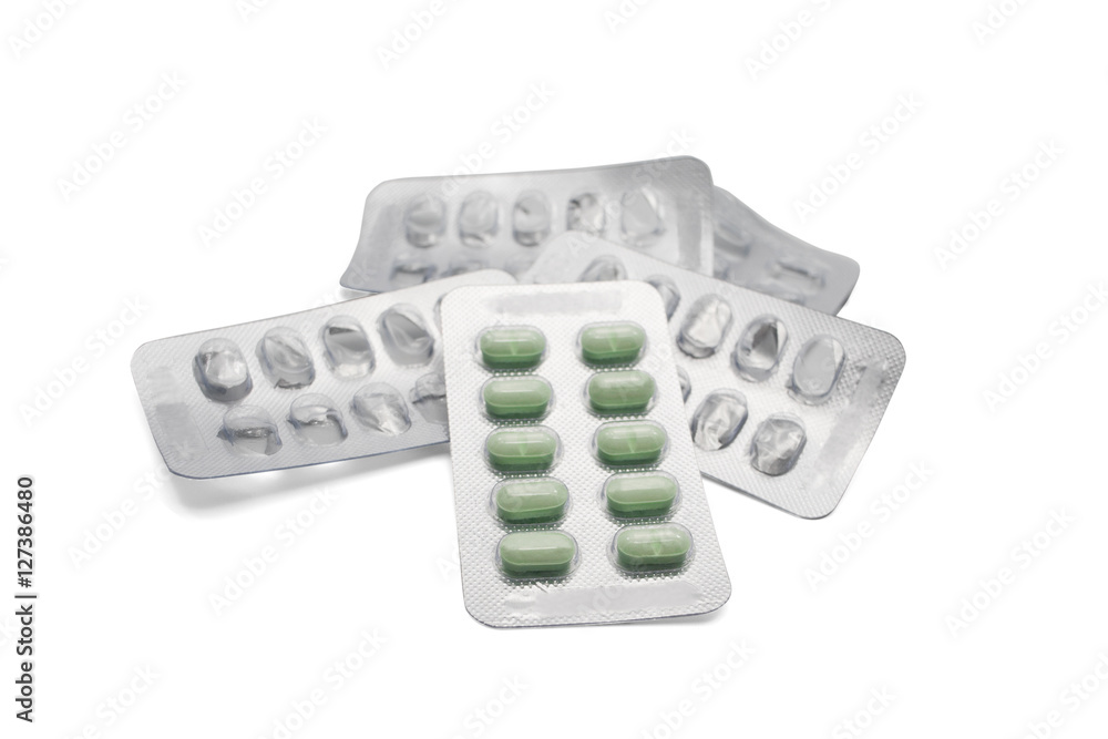 Green pills package on pile of empty pill packages on isolated white background Green pills package on pile of empty pill packages on isolated white background