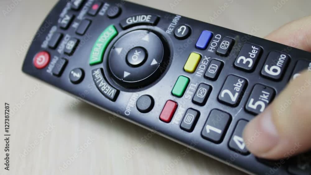 human hand changes the channels on the TV remote control human hand changes the channels on the TV remote control