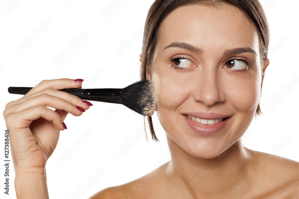 young woman apply makeup base on her face young woman apply makeup base on her face