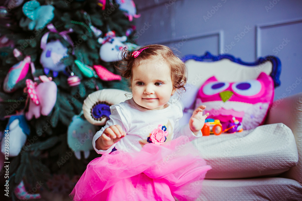 The small girl stands near christmas tree The small girl stands near christmas tree