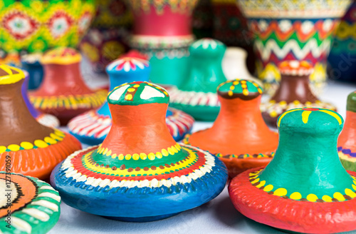 Angled view of still life of colorful painted pottery lids on white background