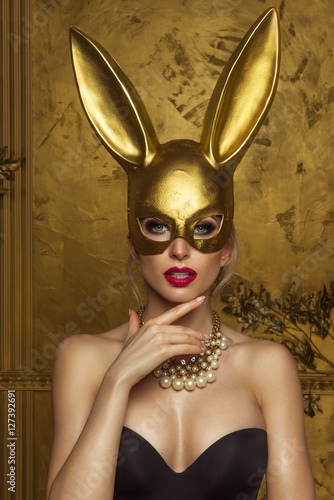 Beautiful blonde young woman in carnival gold rabbit mask with long ears