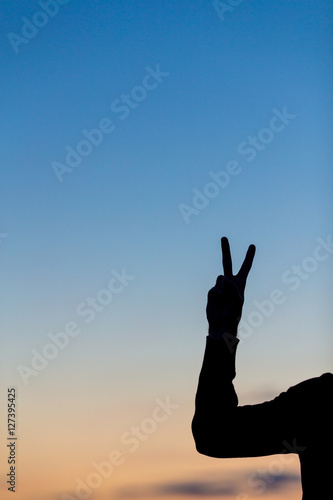 Silhouette of male celebrating with arm up towards the sunrise.