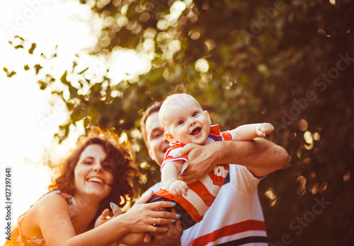 young and happy parents playing with their cute little baby outd photo