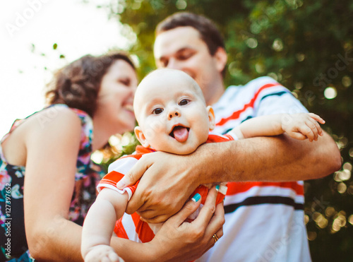 young and happy parents playing with their cute little baby outd