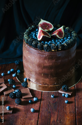 Chocolate cake with fresh blueberry, blackberry and figs on dark rustic background