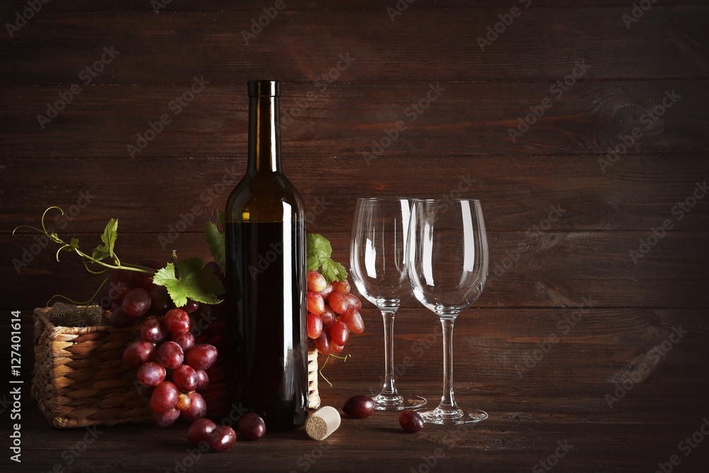 Wine bottle and glasses with grapes on wooden background