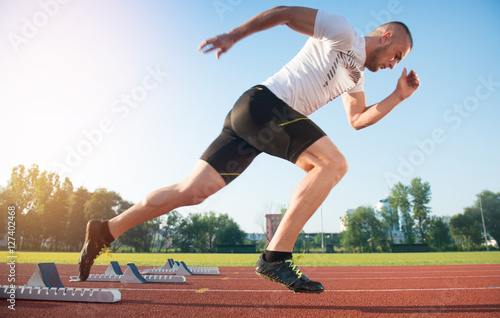Athletic man on track starting to run. Healthy fitness concept with active lifestyle.