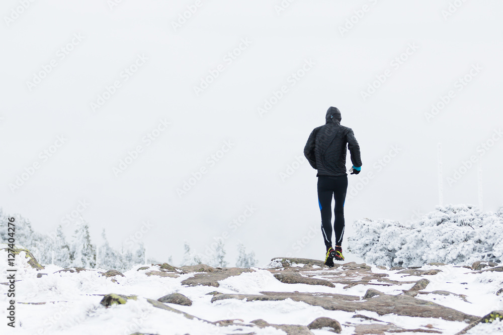 runner in black warm sportswear running in wind and fog on the high mountain trail in the winter runner in black warm sportswear running in wind and fog on the high mountain trail in the winter