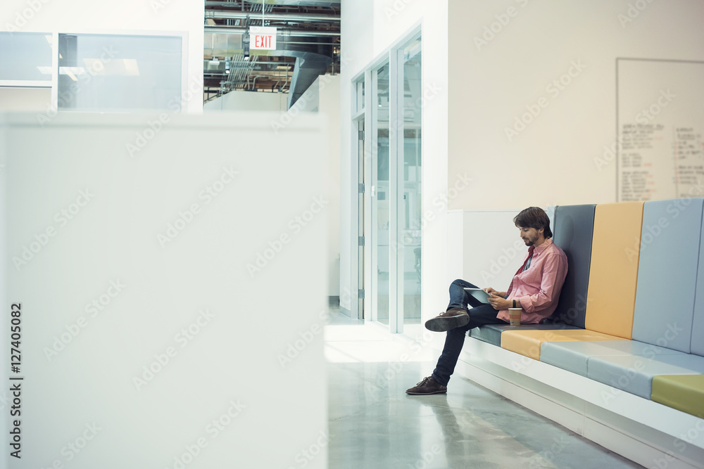 Young businessman sitting in lobby using digital tablet Young businessman sitting in lobby using digital tablet