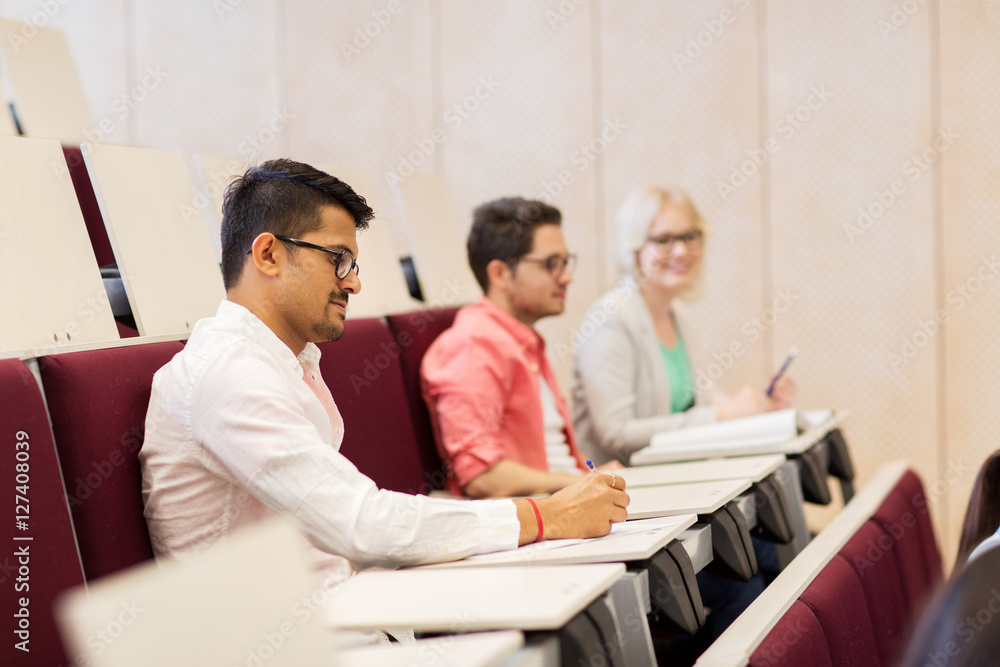 group of students with notebooks in lecture hall group of students with notebooks in lecture hall