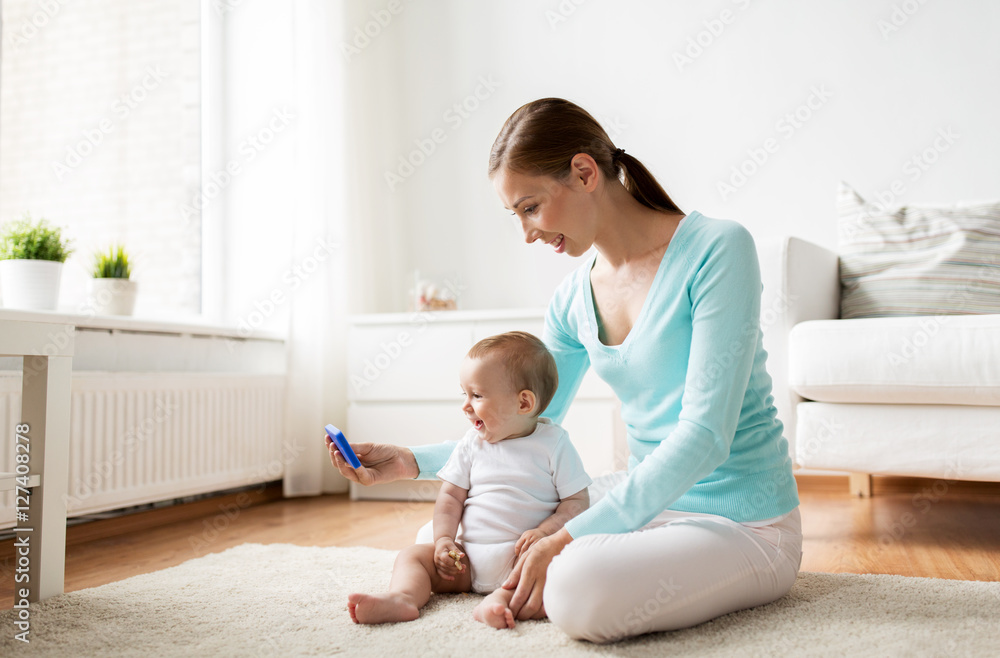 happy mother showing smartphone to baby at home happy mother showing smartphone to baby at home