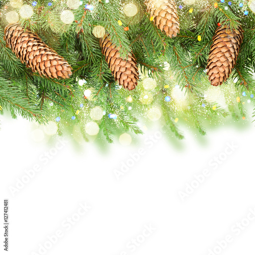 Fresh pine branch with cones and bokeh llights border over white background photo