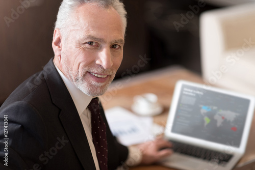 Smiling businessman working with the laptop in the hotel