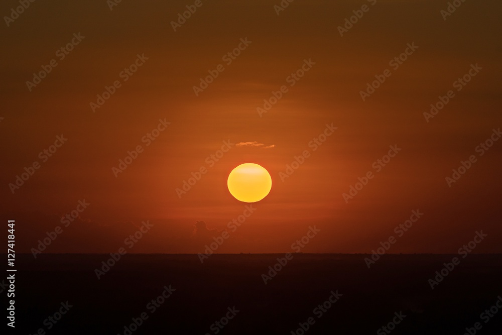 Beautiful sunset over silhouette mountain skyline with orange sky background. Full sunset
Sunset or sunrise yellow sun disc above the tops of the forest trees silhouettes.
