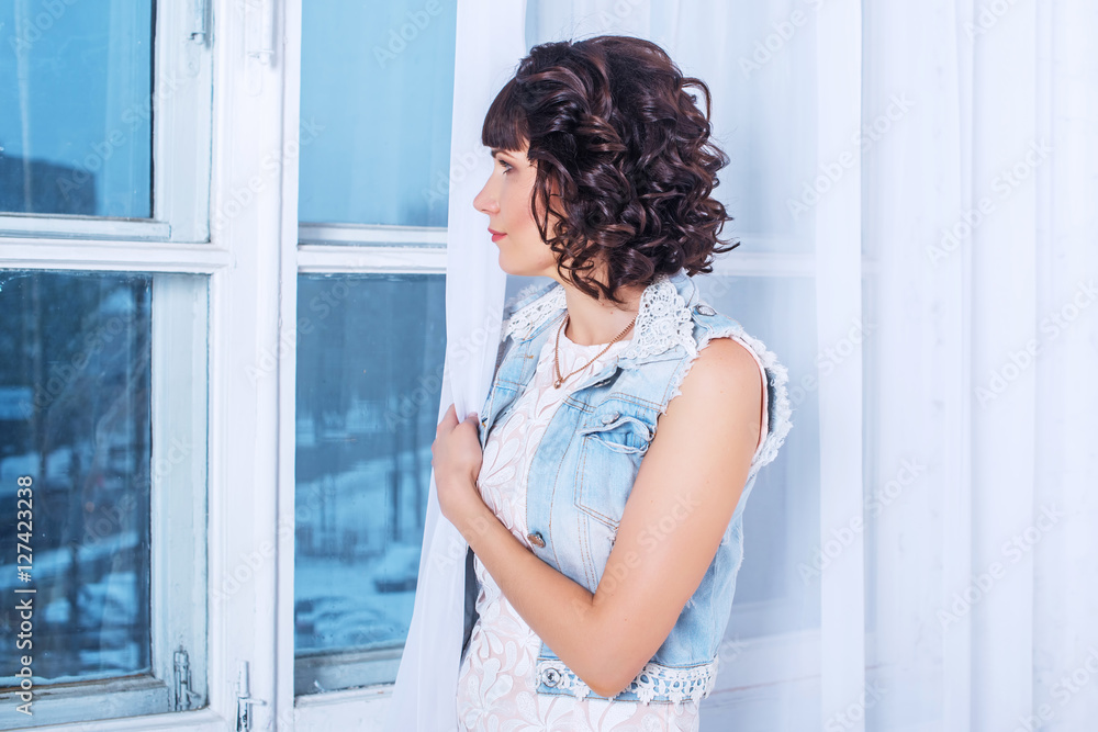 Young beautiful woman standing and waiting sad looking out the window. Young beautiful woman standing and waiting sad looking out the window.