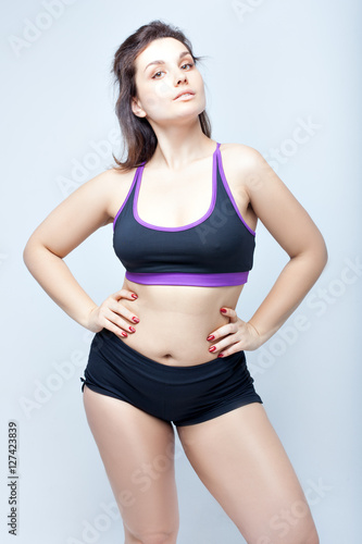 Beautiful plump woman in the sports underwear on a white background