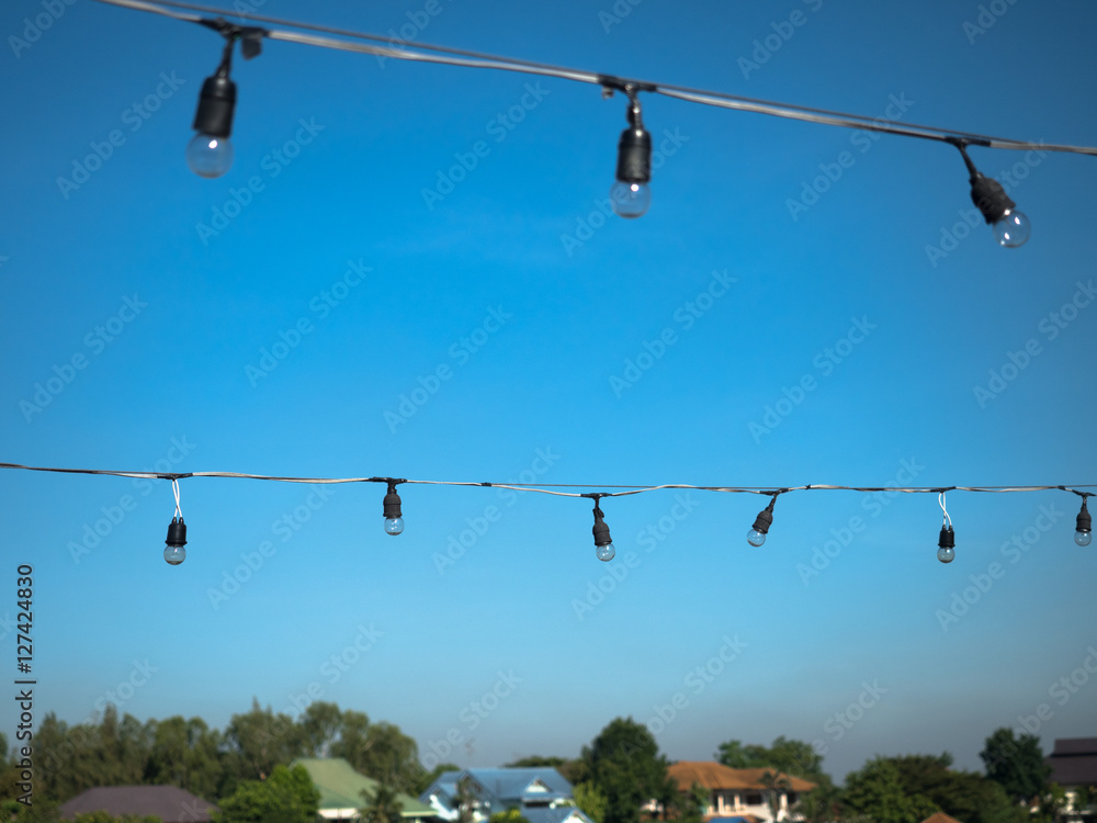Light bulbs hanging on electric wires with blue sky background Light bulbs hanging on electric wires with blue sky background