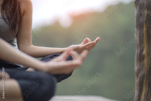 Woman yoga finger acting on hands in soft focus foreground with Nature surrounding