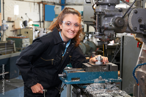 Female Apprentice Engineer Working On Drill In Factory