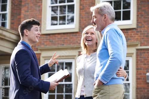 Photography Realtor Showing Mature Couple Around House For Sale
