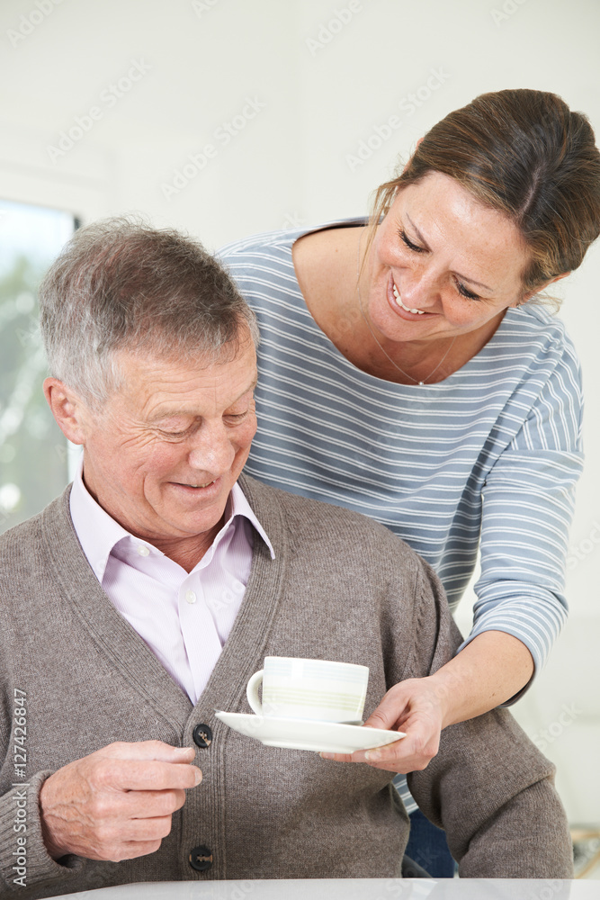 Adult Daughter Bringing Senior Father Hot Drink At Home Adult Daughter Bringing Senior Father Hot Drink At Home