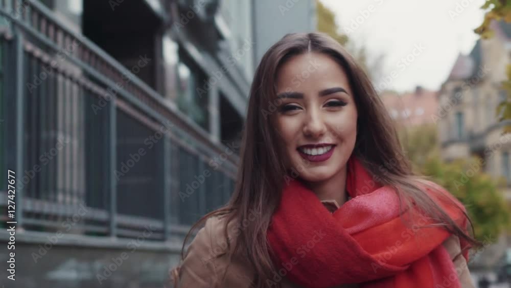 Close up view of extraordinary natural beauty, in a red scarf, and with a cup of coffee. Gorgeous woman smiling towards the camera while walking down the city street. Close up view of extraordinary natural beauty, in a red scarf, and with a cup of coffee. Gorgeous woman smiling towards the camera while walking down the city street.