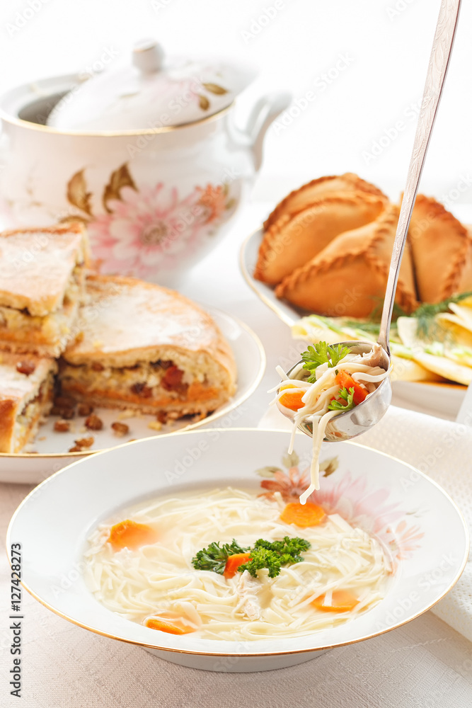 Traditional Tatar holiday table. Tokmach - noodle soup with chicken. Triangles - meat pies and sweet cake. Traditional Tatar holiday table. Tokmach - noodle soup with chicken. Triangles - meat pies and sweet cake.