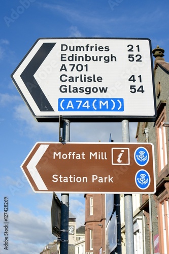 Scottish road sign showing direction to Dumfries, Edinburgh, Carlisle, Glasgow and Moffat Mill, in the town of Moffat, Scotland, UK