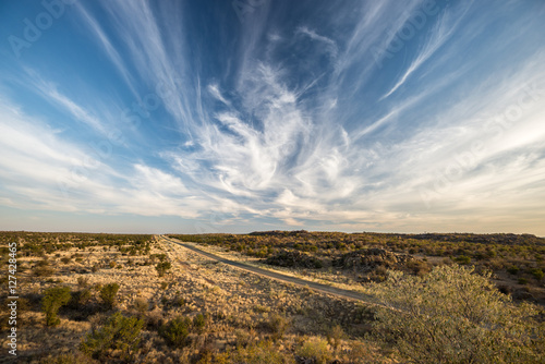 A modern road across Namibian endless plains with magical sky