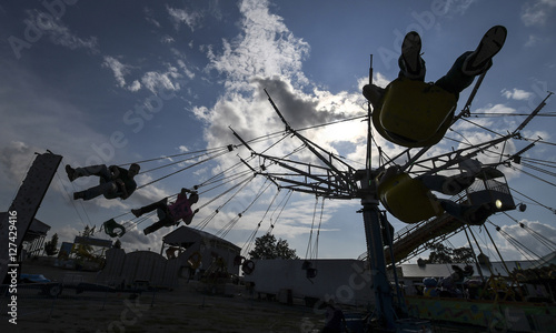 Tableau sur toile Riders are silhouetted on the swings in the midway Friday July 29, 2016