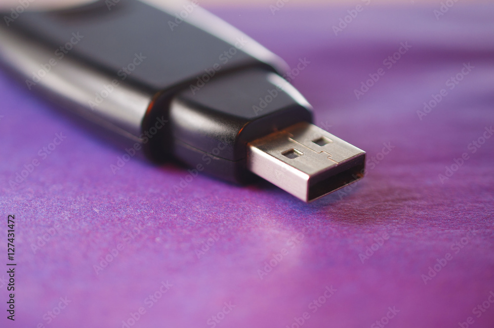 Black flash drive on a purple surface Black flash drive on a purple surface