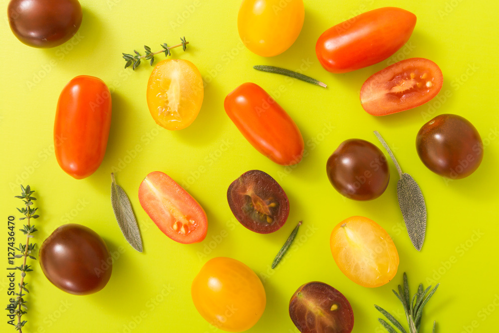 Colorful cherry tomatoes with herbs, on chartreuse yellow background. Colorful cherry tomatoes with herbs, on chartreuse yellow background.